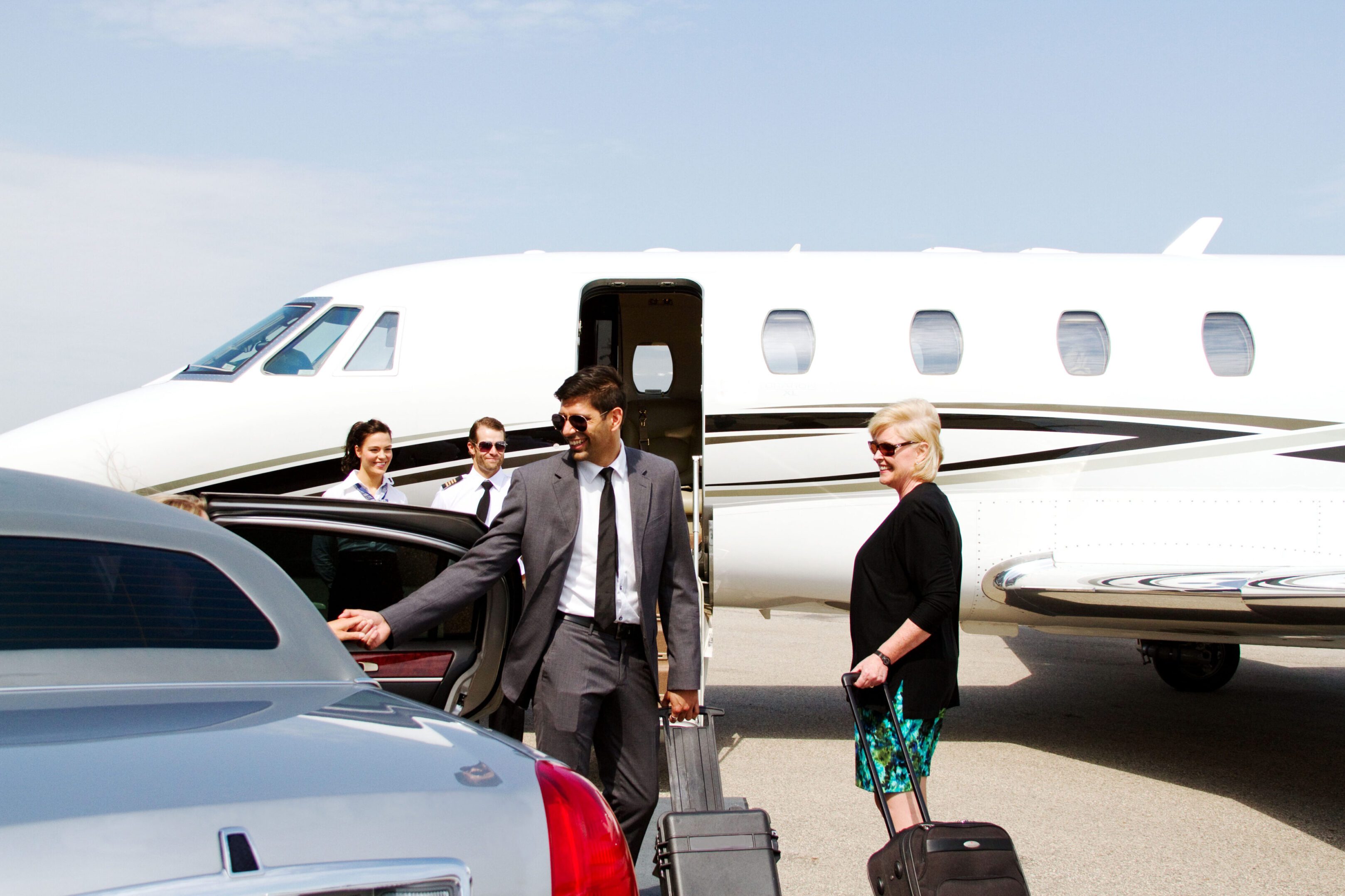 Business travelers with luggage near private jet