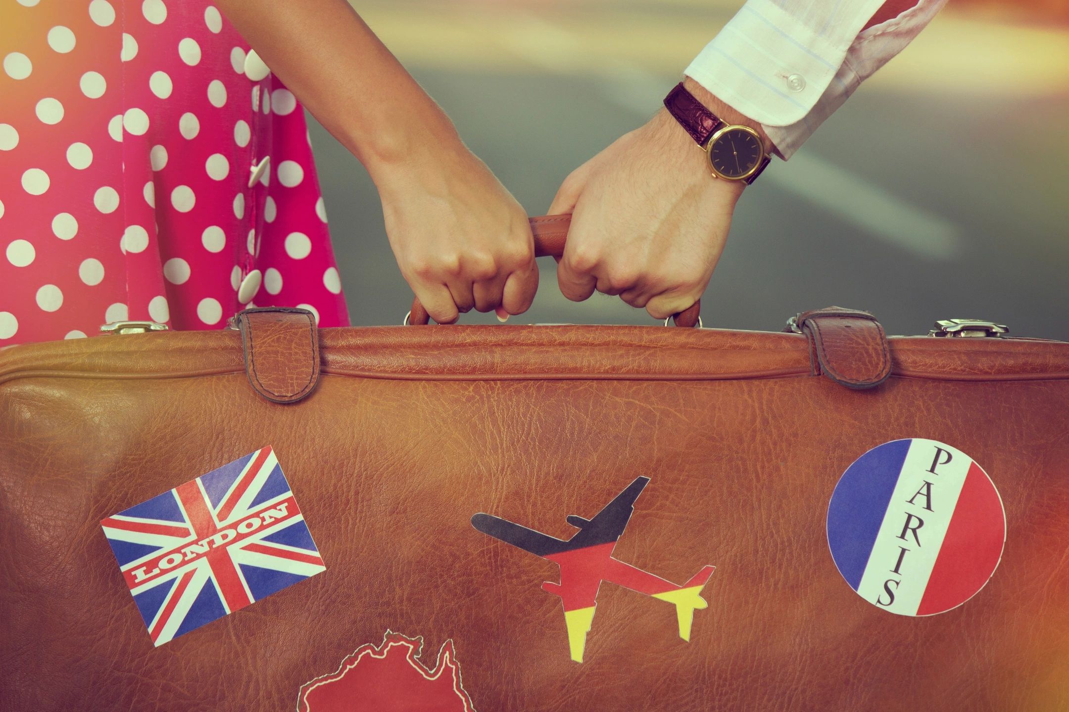 Couple holding vintage suitcase with travel stickers